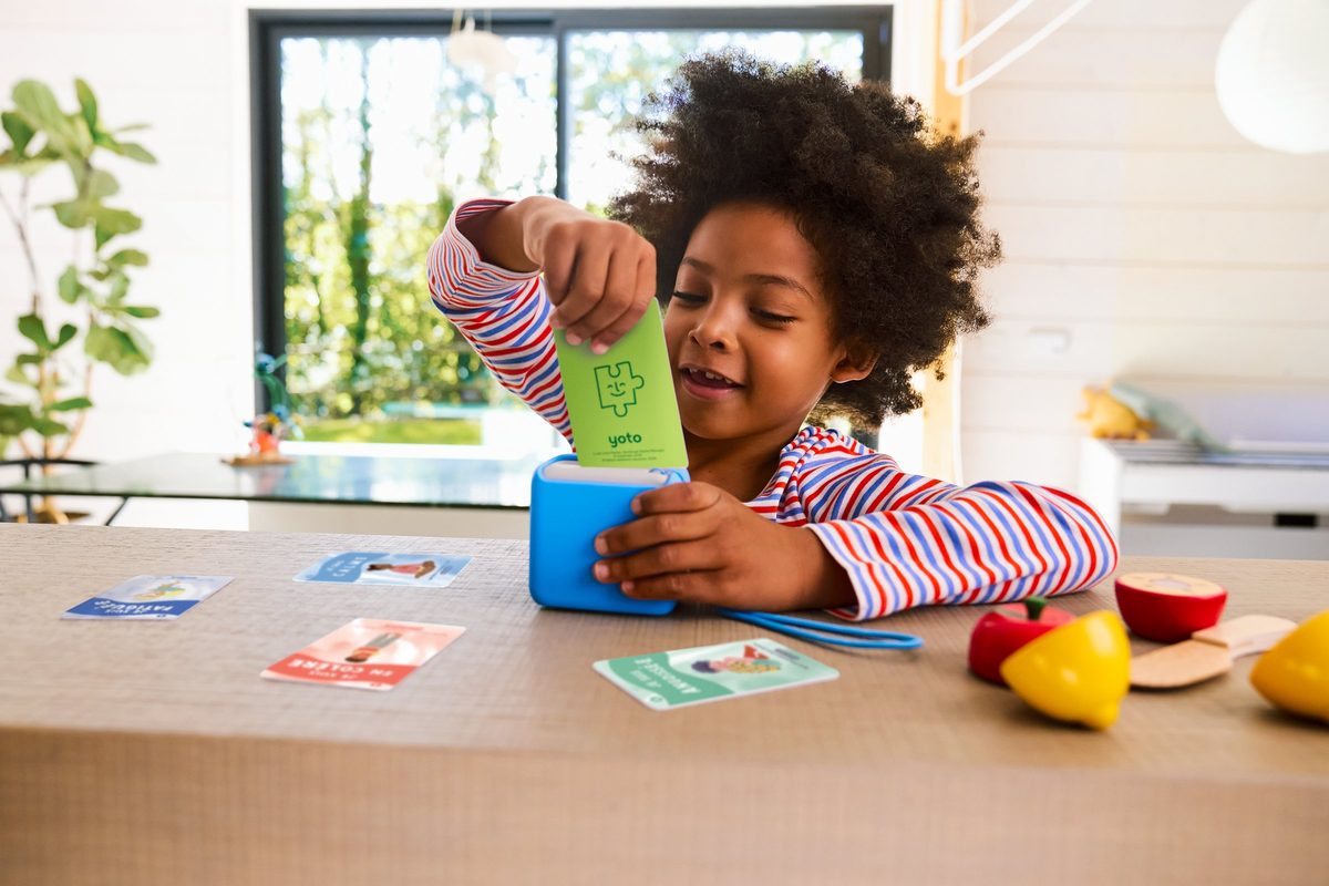 A child slots a story card into the top of a Yoto audio player